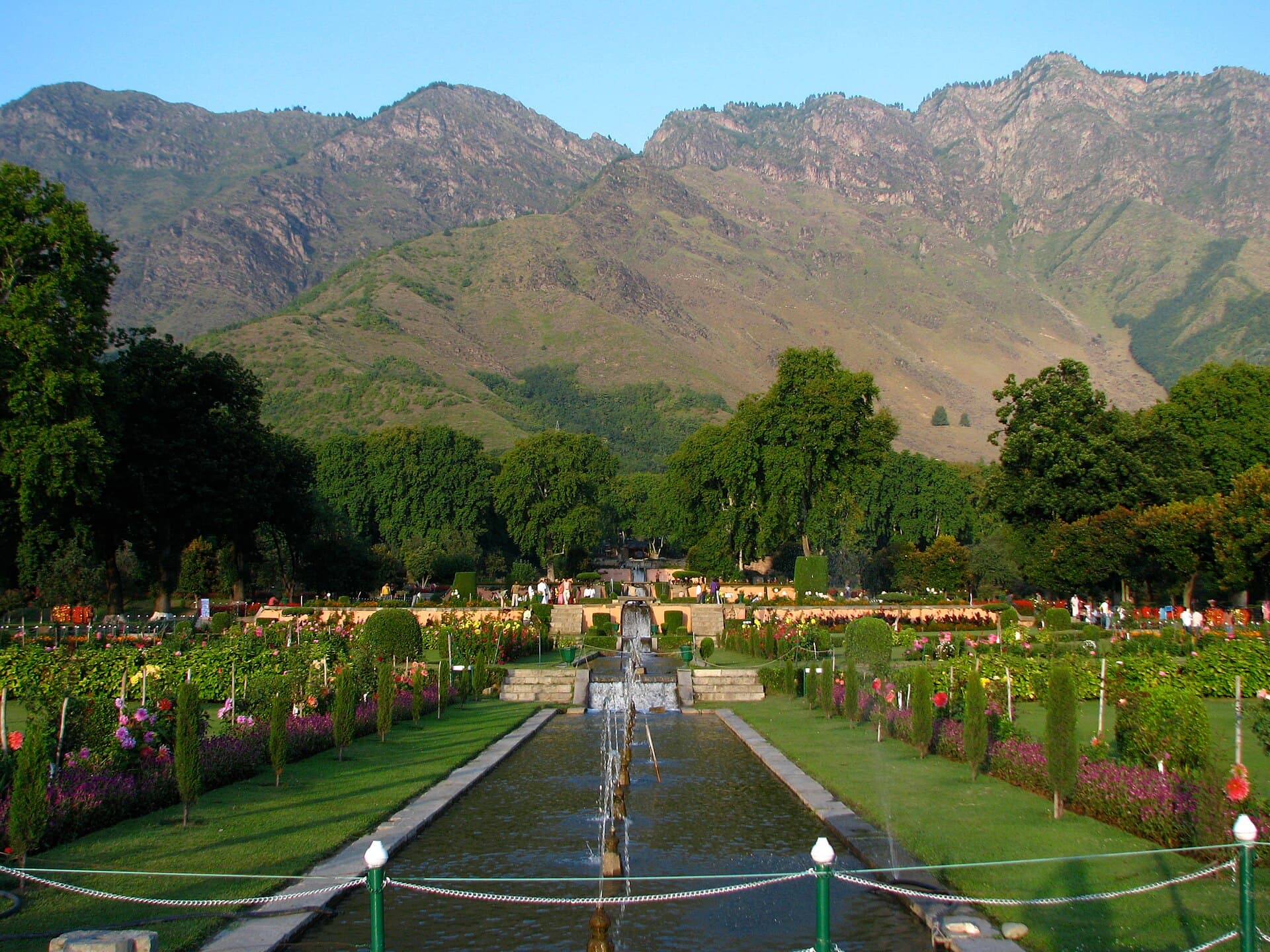 Nishat Bagh's terraced water channel and flower beds stepping down toward the camera, the Zabarwan mountains rising behind