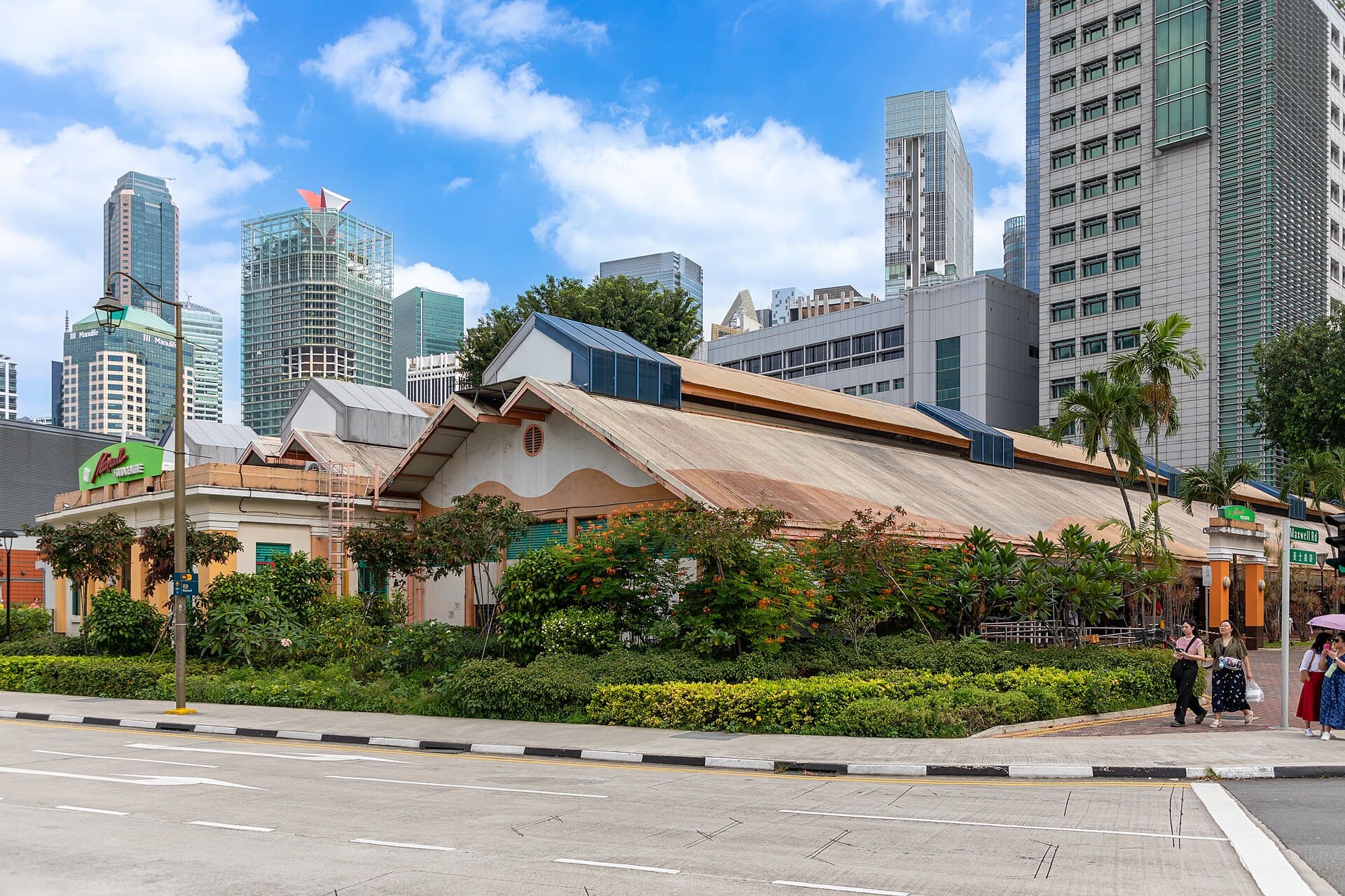 Maxwell Food Centre's low heritage roofline and palm trees set against Singapore's glass-tower skyline