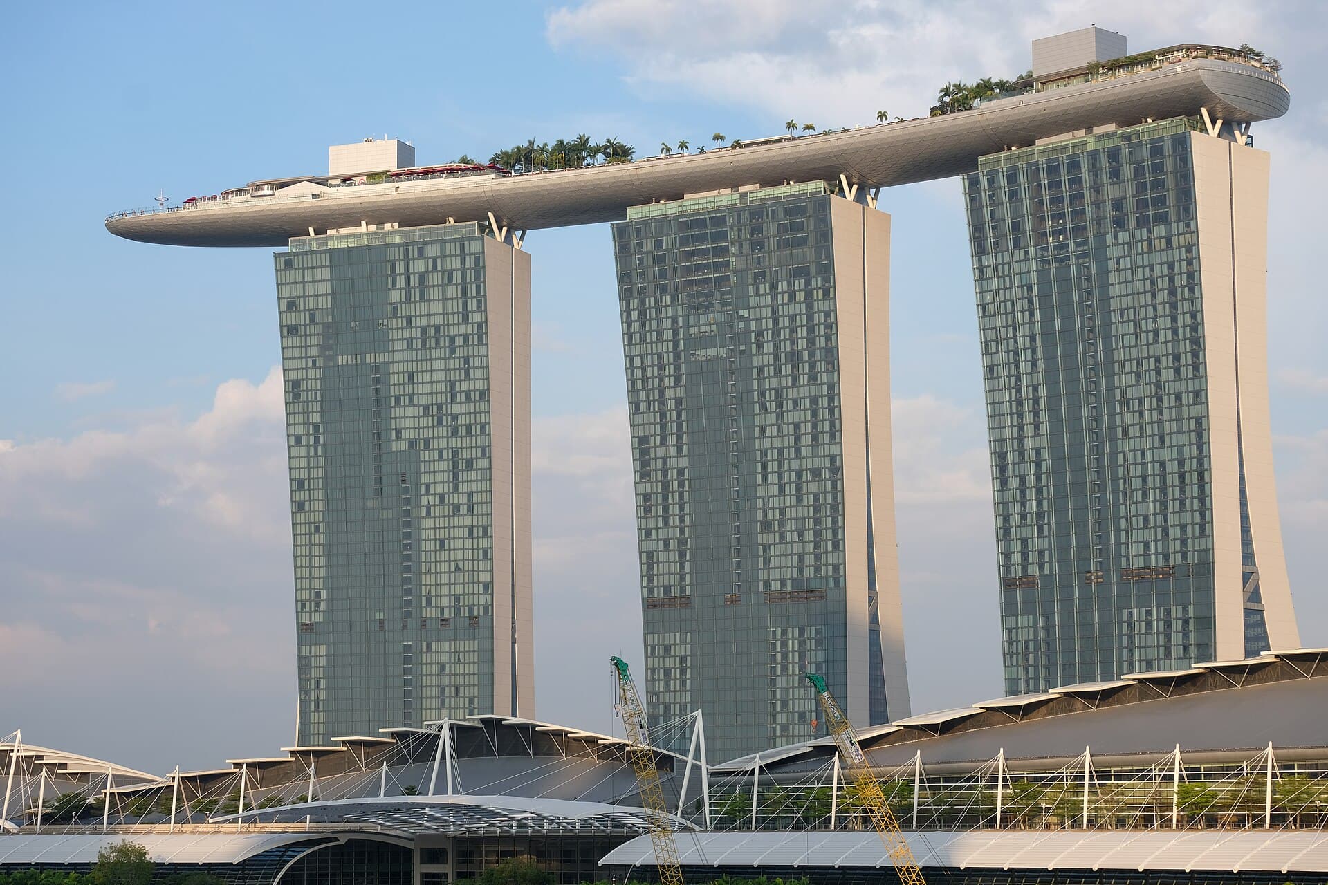 Marina Bay Sands' three towers topped by the ship-shaped SkyPark, palm trees visible along its rooftop edge